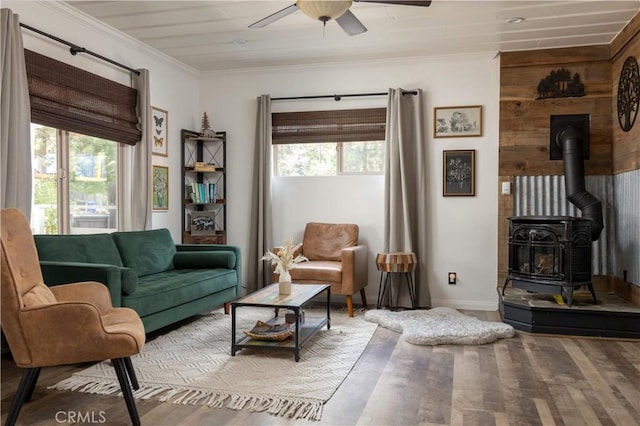 living room featuring ceiling fan, crown molding, and a wood stove