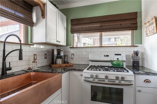 kitchen featuring backsplash, sink, white cabinetry, white gas range, and dark stone counters