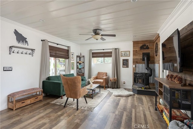 sitting room with ceiling fan, a wood stove, wood-type flooring, and crown molding