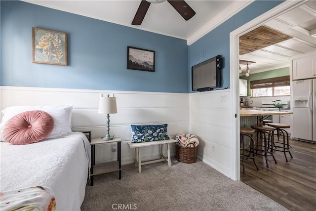 carpeted bedroom with ceiling fan, white refrigerator with ice dispenser, and crown molding