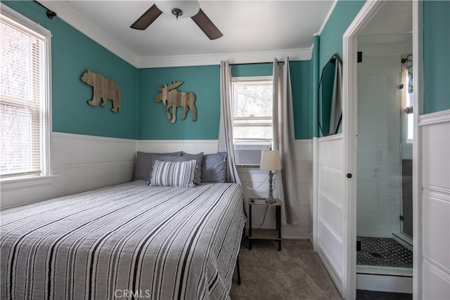 carpeted bedroom featuring ceiling fan, ensuite bathroom, and multiple windows