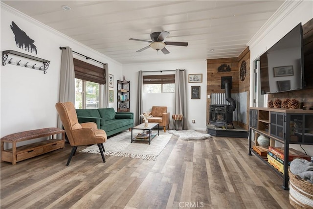 living room with ceiling fan, ornamental molding, a wood stove, and hardwood / wood-style flooring