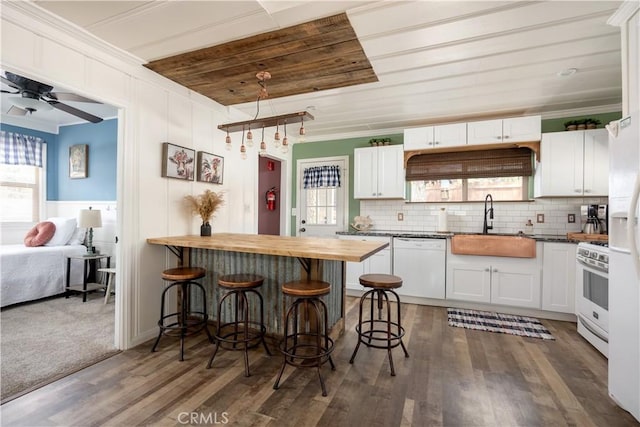 kitchen with white cabinetry, a kitchen breakfast bar, white appliances, and butcher block counters