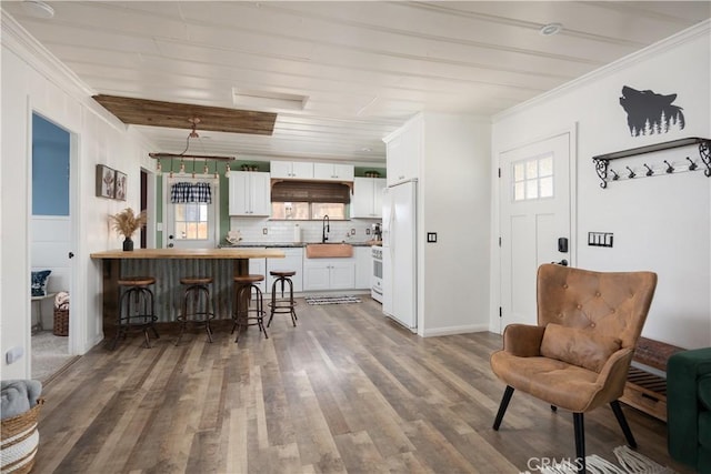 kitchen featuring backsplash, a kitchen breakfast bar, dark hardwood / wood-style flooring, white cabinets, and sink