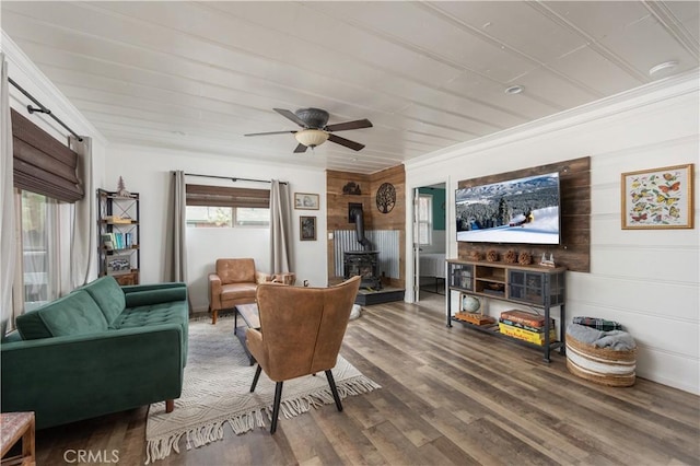 living room featuring ceiling fan, ornamental molding, a wood stove, and hardwood / wood-style floors