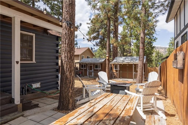 wooden terrace with a patio area, a fire pit, and a storage unit