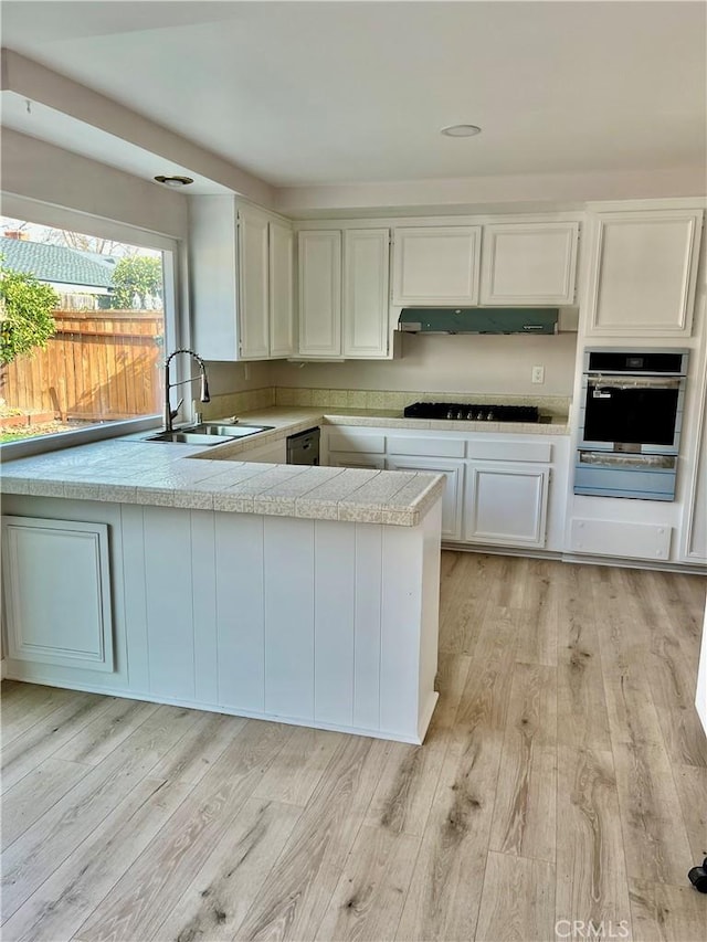 kitchen with white cabinetry, appliances with stainless steel finishes, sink, and light wood-type flooring