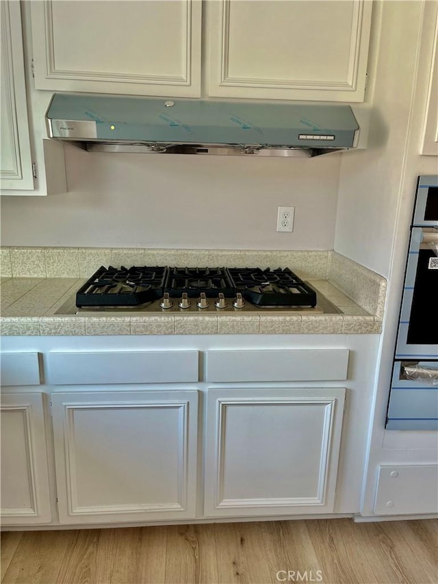 kitchen featuring white cabinetry, appliances with stainless steel finishes, and exhaust hood