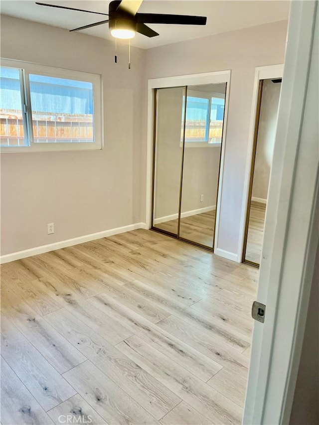 unfurnished bedroom featuring two closets, light hardwood / wood-style flooring, and ceiling fan