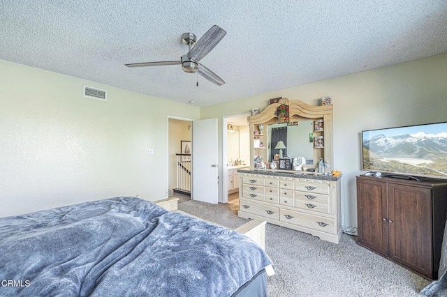 carpeted bedroom with a textured ceiling, ceiling fan, and connected bathroom