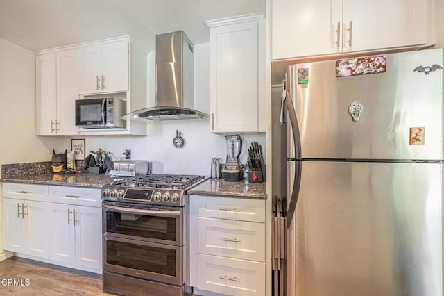 kitchen featuring white cabinets, appliances with stainless steel finishes, light hardwood / wood-style flooring, and wall chimney exhaust hood