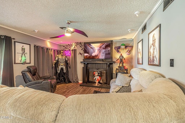 cinema room featuring ceiling fan, wood-type flooring, crown molding, and a textured ceiling