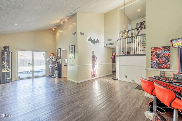 interior space featuring high vaulted ceiling, rail lighting, a textured ceiling, and hardwood / wood-style floors