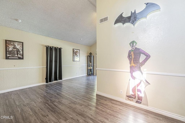 empty room featuring a textured ceiling, lofted ceiling, and hardwood / wood-style floors