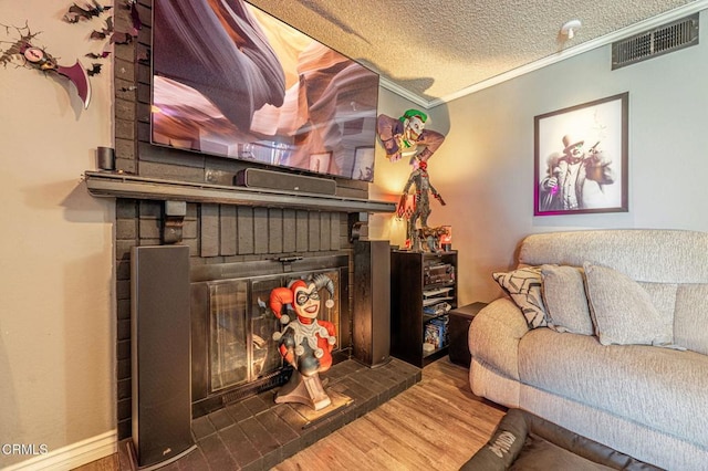 living room with a fireplace, a textured ceiling, ornamental molding, and hardwood / wood-style flooring