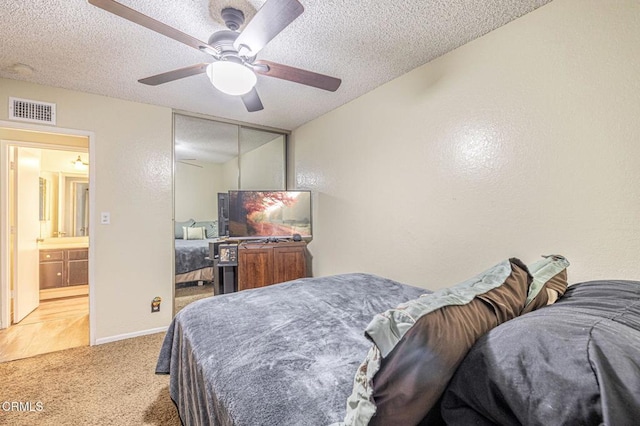 bedroom with visible vents, ceiling fan, light carpet, and a textured ceiling