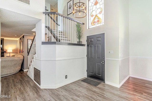 entrance foyer with a high ceiling, wood finished floors, visible vents, baseboards, and stairway