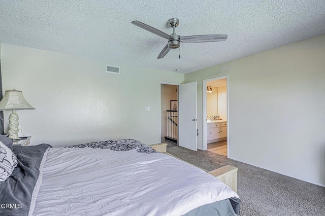 bedroom with visible vents, ensuite bathroom, light carpet, ceiling fan, and a textured ceiling