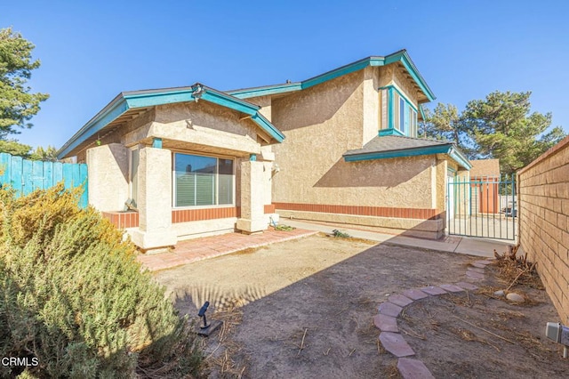 back of property with a gate, a patio area, a fenced backyard, and stucco siding