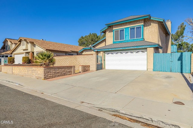 traditional home with a garage, driveway, fence, and stucco siding