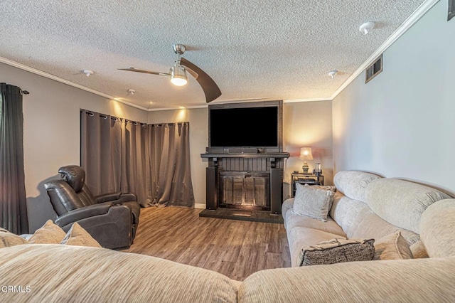 living area featuring a textured ceiling, visible vents, wood finished floors, and ornamental molding