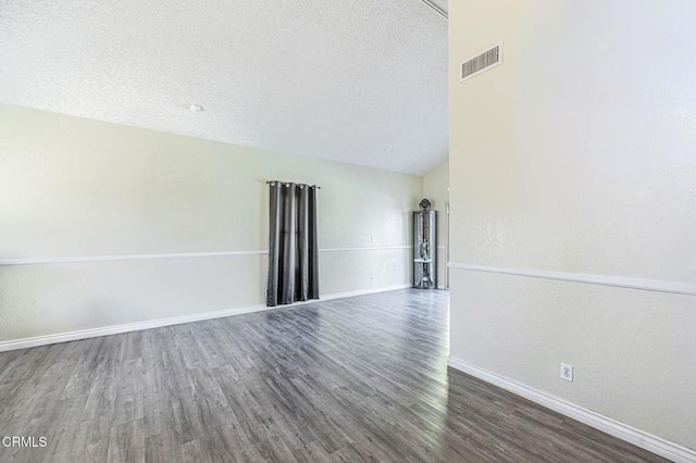 empty room with baseboards, a textured ceiling, visible vents, and dark wood-style flooring