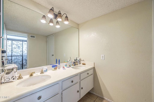 full bathroom with double vanity, a textured ceiling, visible vents, and a sink