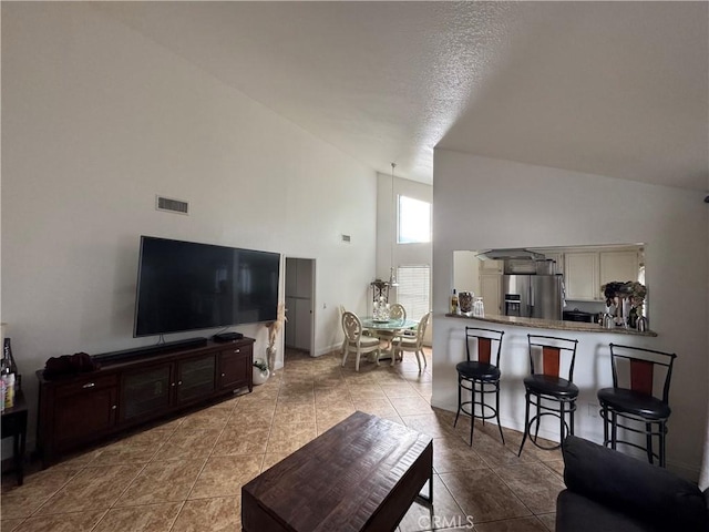 tiled living room featuring high vaulted ceiling and a textured ceiling