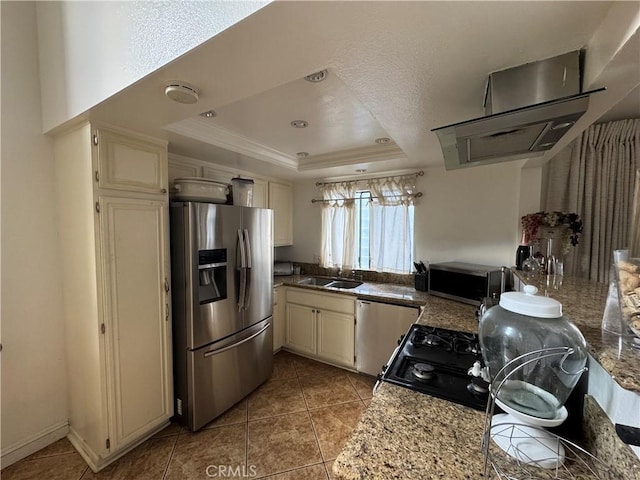 kitchen with light tile patterned floors, a tray ceiling, stainless steel appliances, and cream cabinetry