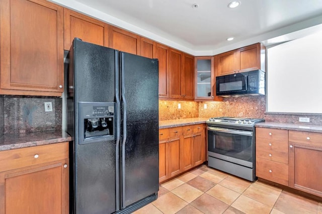 kitchen featuring black appliances, light stone countertops, tasteful backsplash, and light tile patterned flooring