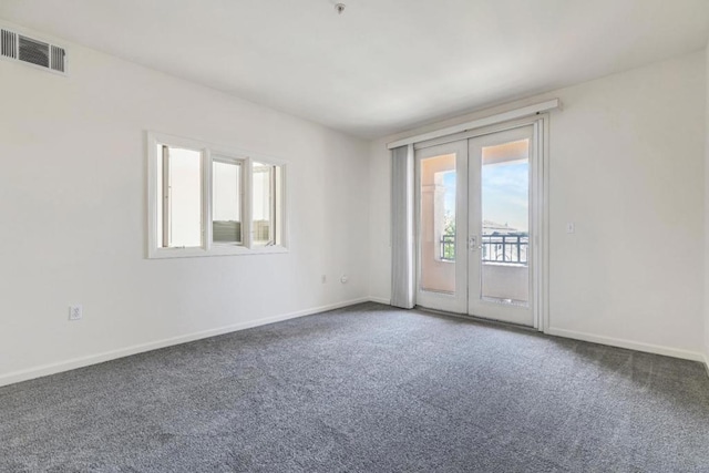 spare room featuring dark carpet and french doors