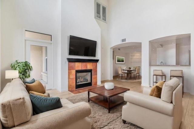 living room with a towering ceiling, light hardwood / wood-style floors, and a fireplace