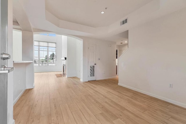 unfurnished room featuring light hardwood / wood-style floors and a tray ceiling