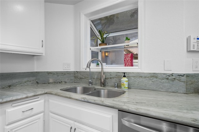 kitchen featuring stainless steel dishwasher, light stone countertops, sink, and white cabinetry