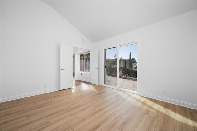 spare room with high vaulted ceiling and light wood-type flooring