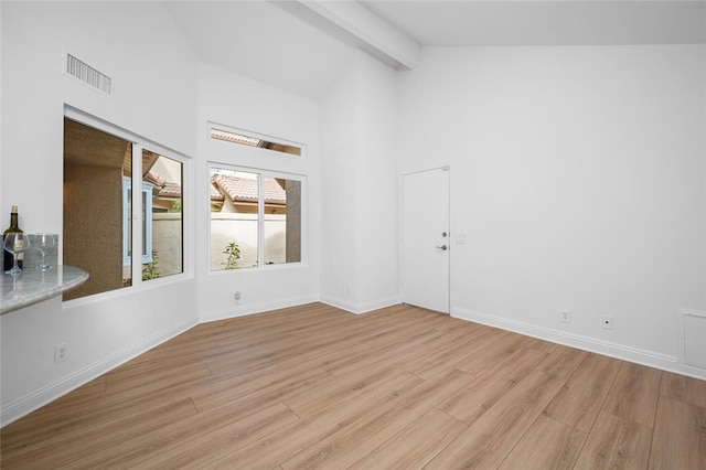 empty room with lofted ceiling with beams and light hardwood / wood-style flooring