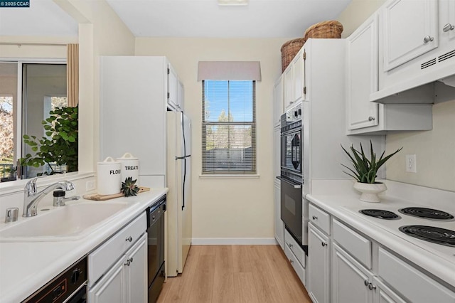 kitchen with sink, black appliances, white cabinetry, and light hardwood / wood-style flooring