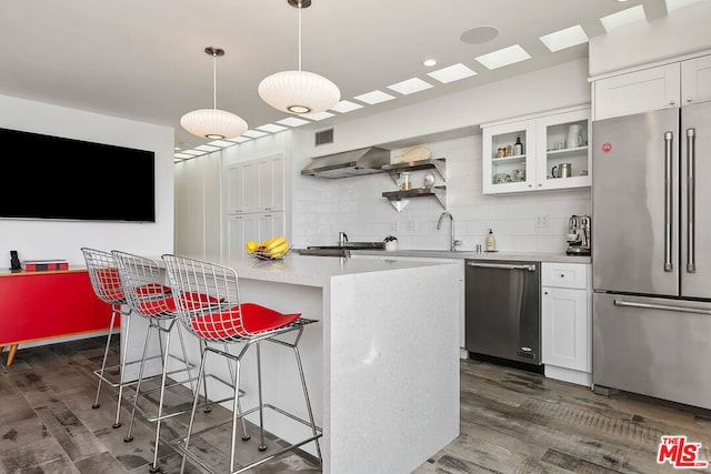 kitchen with white cabinets, a center island, decorative light fixtures, stainless steel appliances, and backsplash