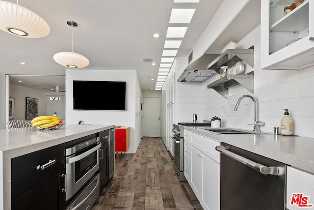 kitchen featuring sink, hanging light fixtures, appliances with stainless steel finishes, dark wood-type flooring, and white cabinets