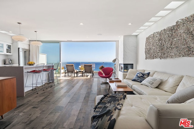 living room with a water view, a wall of windows, dark hardwood / wood-style floors, and a premium fireplace