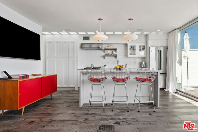 kitchen featuring dark hardwood / wood-style floors, high end refrigerator, pendant lighting, a breakfast bar area, and white cabinets