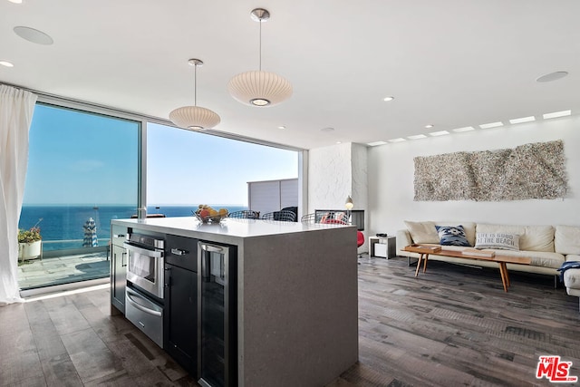 kitchen featuring floor to ceiling windows, a center island, a water view, and wine cooler