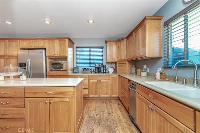 kitchen featuring light wood-style flooring, appliances with stainless steel finishes, light countertops, a sink, and recessed lighting