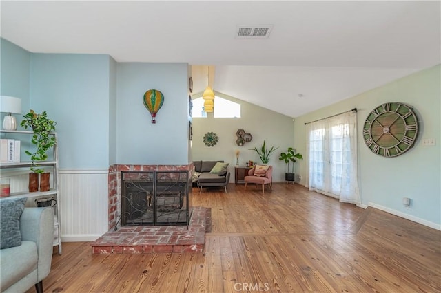 living room with a healthy amount of sunlight, visible vents, vaulted ceiling, and wood finished floors