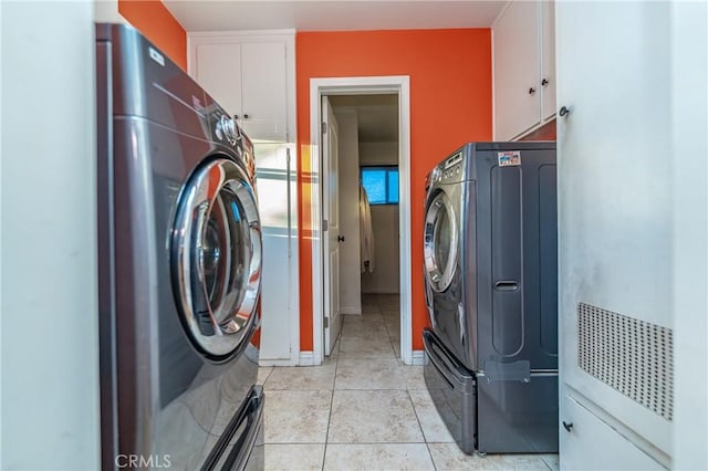 clothes washing area with cabinet space, baseboards, light tile patterned floors, and washer / clothes dryer