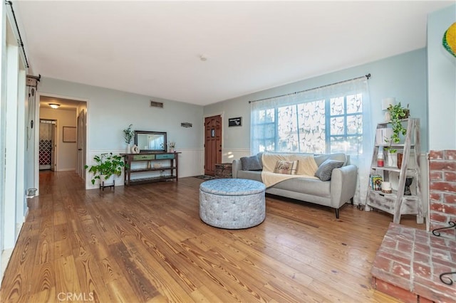 living area with wainscoting, wood finished floors, and visible vents