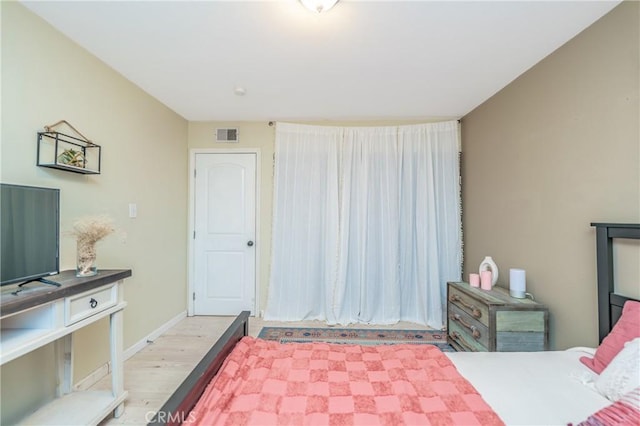 bedroom featuring visible vents, baseboards, and wood finished floors