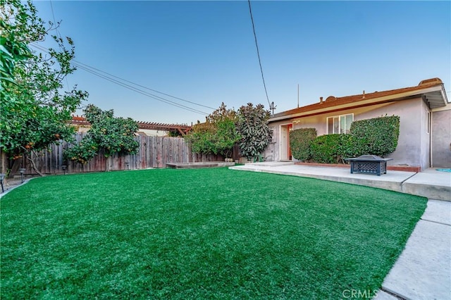 view of yard with a fire pit, a patio, and a fenced backyard