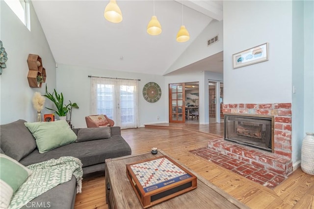 living room with visible vents, wood finished floors, a fireplace, high vaulted ceiling, and beam ceiling