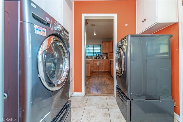 laundry area with light tile patterned flooring, cabinet space, washer / dryer, and baseboards